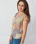 Woman wearing a colorful floral blouse and blue jeans on a white background