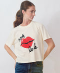 Woman wearing a white t-shirt with red lips and text design on a plain background
