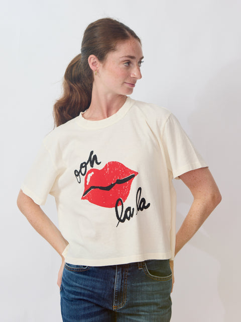 Woman wearing a white t-shirt with red lips and text design on a plain background