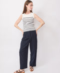 Sleeveless ecru top with horizontal navy stripes paired with loose navy pants and brown sandals.