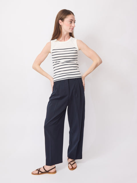 Sleeveless ecru top with horizontal navy stripes paired with loose navy pants and brown sandals.