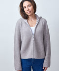 Woman wearing a gray zip-up hoodie against a light background