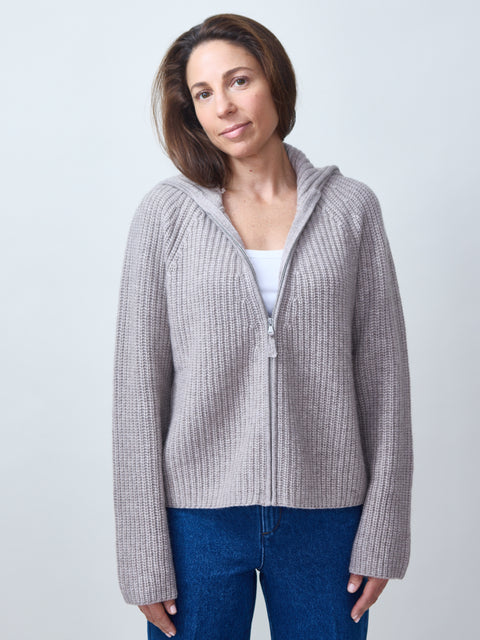 Woman wearing a gray zip-up hoodie against a light background