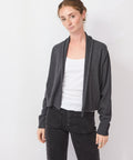 Woman wearing a gray cardigan over a white shirt and black pants on a white background