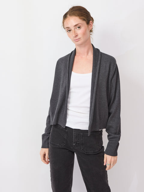 Woman wearing a gray cardigan over a white shirt and black pants on a white background