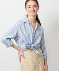 Blue and white vertical striped button-up shirt with tied front and rolled sleeves.