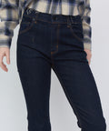 High-waisted indigo blue denim jeans with orange stitching and classic five-pocket design worn with a plaid shirt.