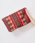 Colorful striped clutch held by a hand on a white background
