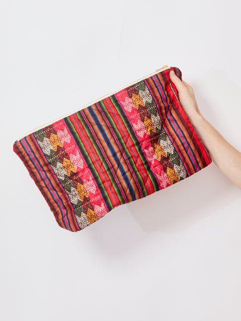 Colorful striped clutch held by a hand on a white background