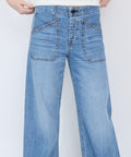 Light blue denim jeans with wide legs, front patch pockets, and stitched detailing on the hips.