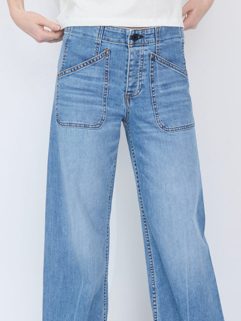 Light blue denim jeans with wide legs, front patch pockets, and stitched detailing on the hips.