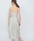Light cream midi dress with thin straps and small orange floral print, pleated skirt detail.