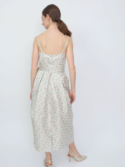 Light cream midi dress with thin straps and small orange floral print, pleated skirt detail.