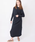 Long British navy dress with long sleeves, relaxed fit, and round neckline, worn with brown strappy sandals.