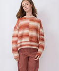 Person wearing a striped sweater and brown pants against a white background