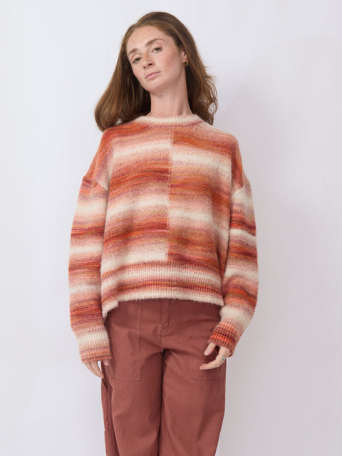 Person wearing a striped sweater and brown pants against a white background
