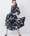 Black dress with bold white floral graphics, long sleeves, flowing skirt, and button-up front.