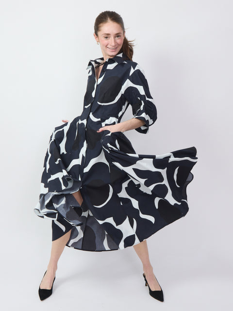 Black dress with bold white floral graphics, long sleeves, flowing skirt, and button-up front.