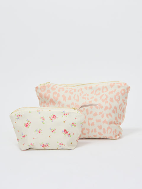 Two floral-patterned makeup pouches in soft ecru tones, one smaller with delicate rose prints, one larger with subtle peach.