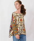 Woman wearing a colorful patterned blouse with a plain background
