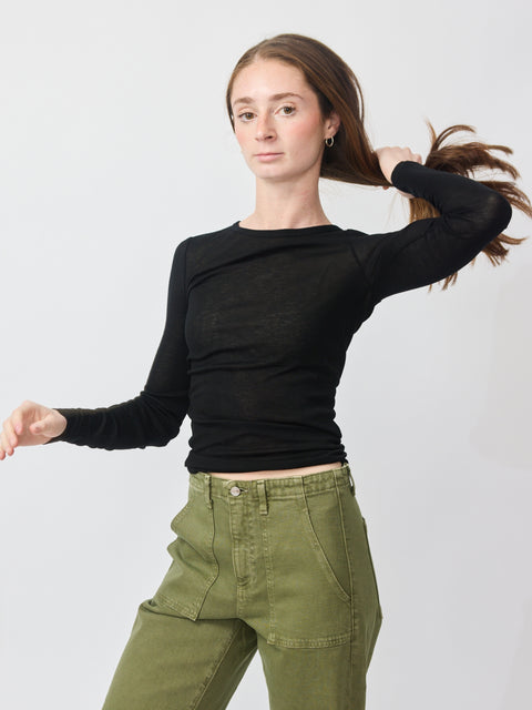 Black long-sleeve fitted t-shirt with a round neckline worn tucked into olive green cargo pants.