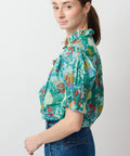 Turquoise floral short-sleeve blouse with puffed sleeves and button-up front.