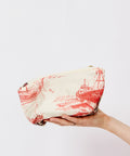 Hand holding a wrapped package with red and black design on a white background
