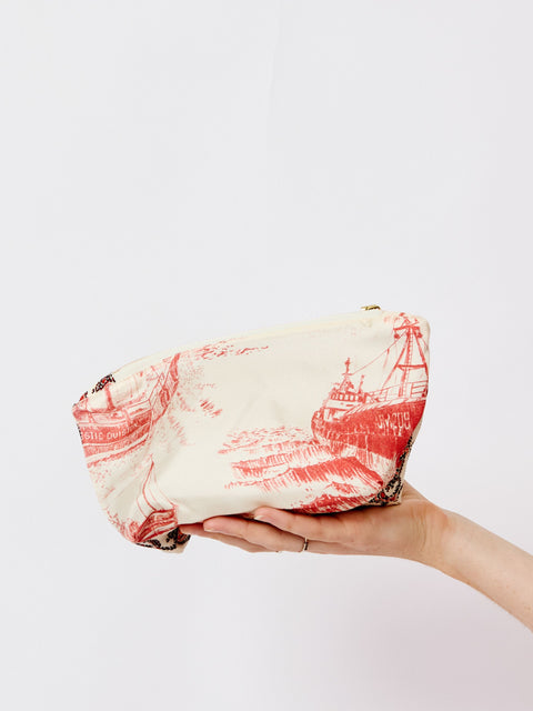 Hand holding a wrapped package with red and black design on a white background