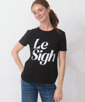 Person wearing a black t-shirt with 'Le Sigh' text on a plain background