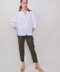White oversized button-up shirt with long sleeves and a relaxed fit, paired with olive green cropped pants and mustard.