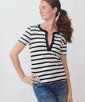 Woman wearing a black and white striped shirt with blue jeans on a plain background