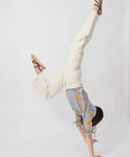 Off-white denim jeans with a straight-leg fit worn by a person doing a handstand, paired with strappy brown sandals.