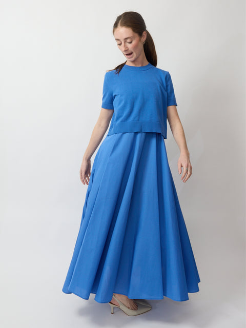 Blue short-sleeve maxi dress with layered bodice and flowy skirt worn with beige heels.
