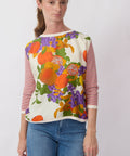 Woman wearing a colorful fruit-themed top with a plain background