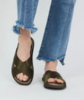 Olive satin crisscross strap sandals with open toe and flat sole worn with frayed hem blue jeans.