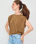 Woman wearing a brown sleeveless top and blue jeans against a white background