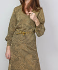 woman in metallic jacquard knit dress with gold studded belt