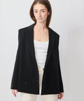 Black double-breasted blazer with structured shoulders and tailored fit worn over a white top.