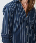 Navy button-up shirt with white vertical stripes and rolled-up sleeves.