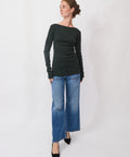 Woman wearing a black long-sleeve top and blue jeans on a white background