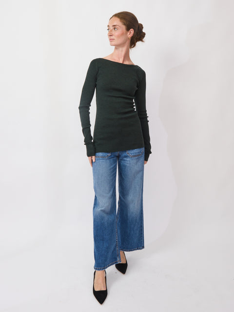 Woman wearing a black long-sleeve top and blue jeans on a white background