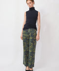 Woman wearing a black sleeveless top and camouflage pants on a white background