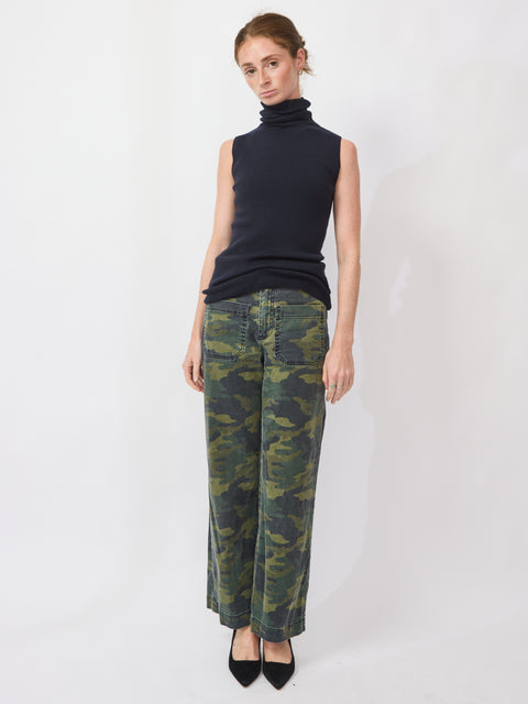 Woman wearing a black sleeveless top and camouflage pants on a white background
