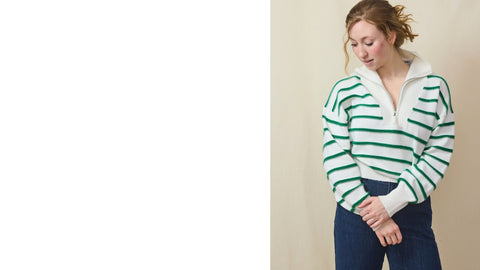 Tall blond woman wears a striped cotton/cashmere ¼ zip sweater and dark high waited jeans.