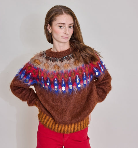 Woman wearing a brown sweater with colorful patterns on a plain background