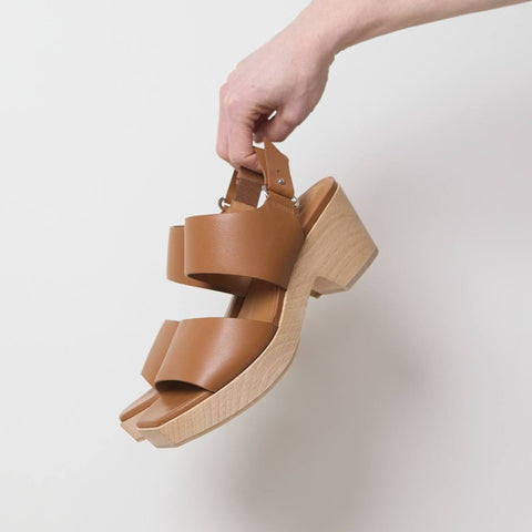 A pair of clog style sandals in brown leather, and a wooden block heel