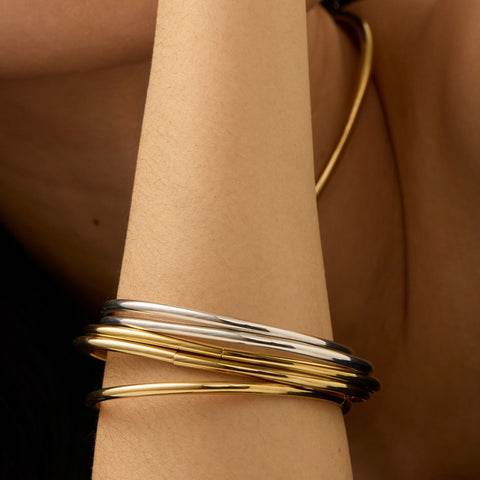 Woman wears a 5-pack bangle set in gold and silver