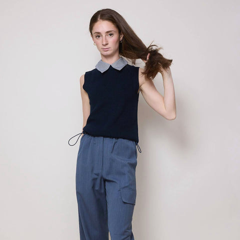 Elegant young woman wears a navy sweater vest with detachable shirt collar and a pair of blue cargo pants 