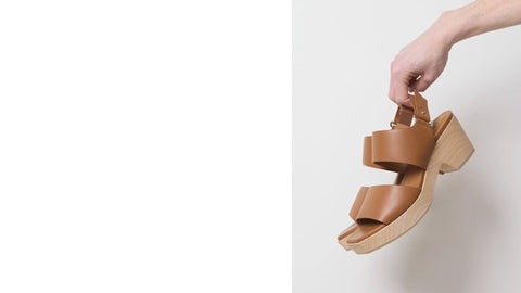 A pair of clog style sandals in brown leather, and a wooden block heel