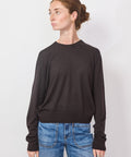 Person wearing a black sweater and blue jeans against a white background